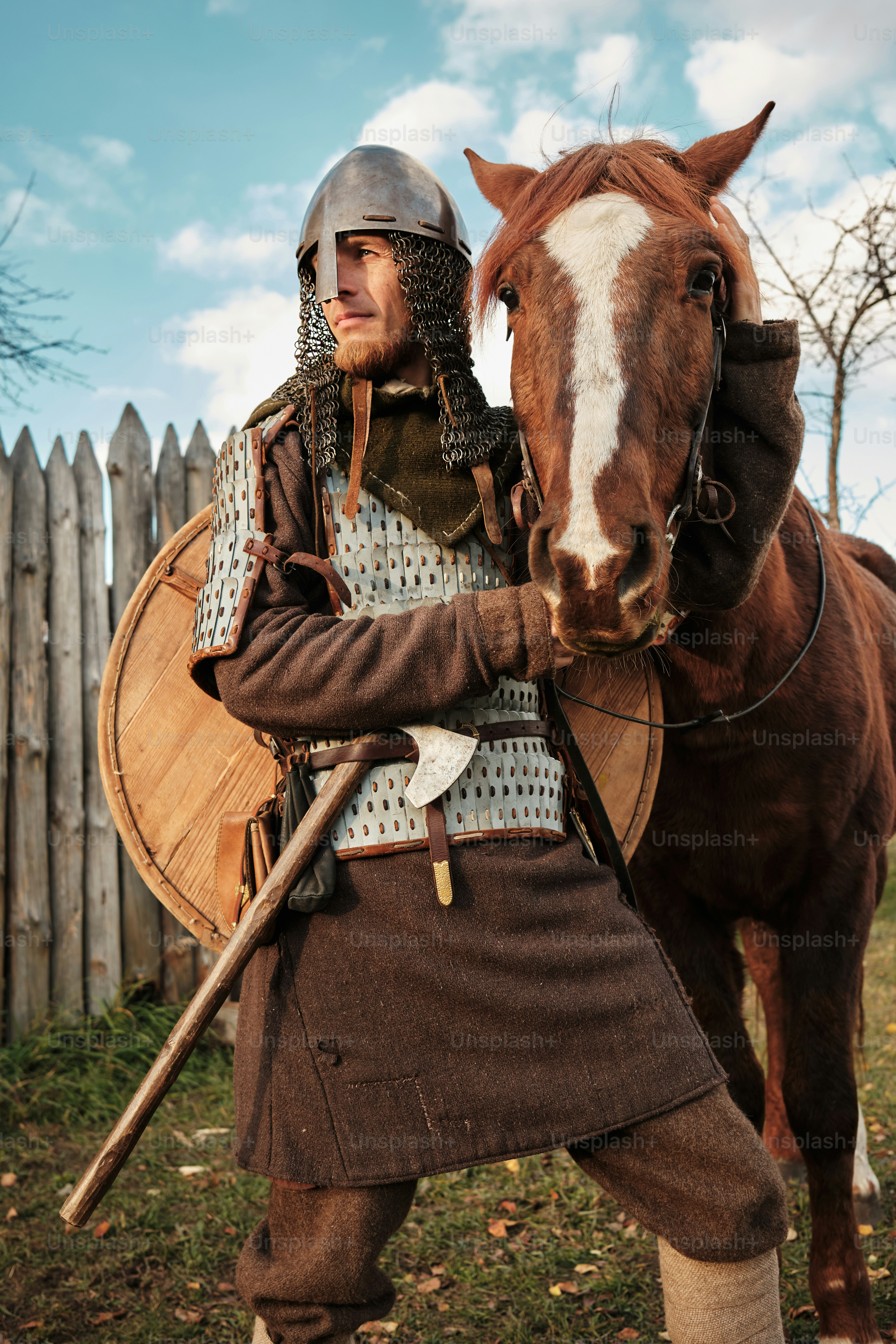 a man in a medieval outfit standing next to a horse
