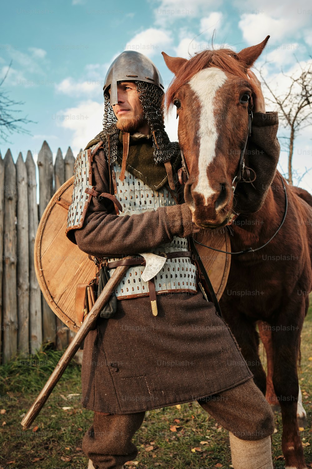 um homem com uma roupa medieval ao lado de um cavalo