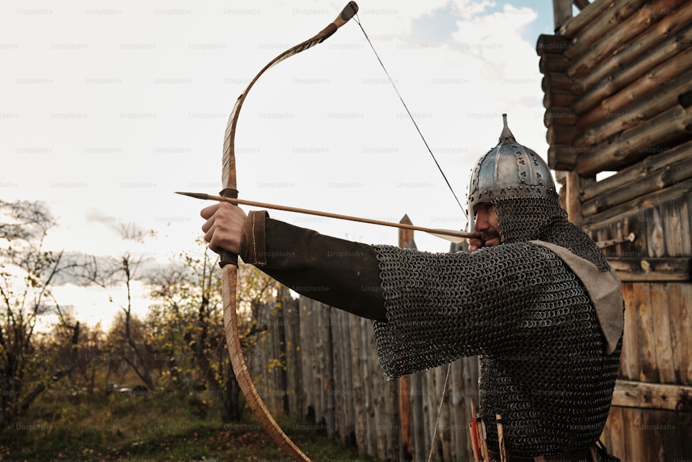 Un hombre vestido con armadura que sostiene un arco y una flecha