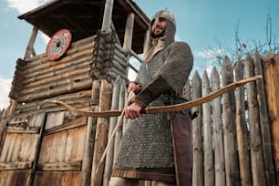 um homem vestido com roupas medievais segurando um arco e flecha