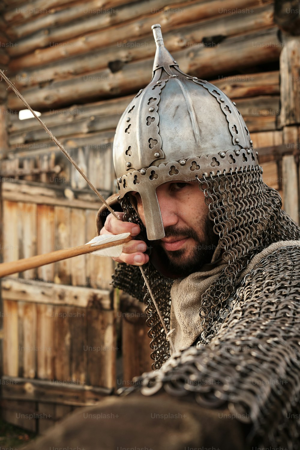 a man in a chain mail outfit holding a wooden stick