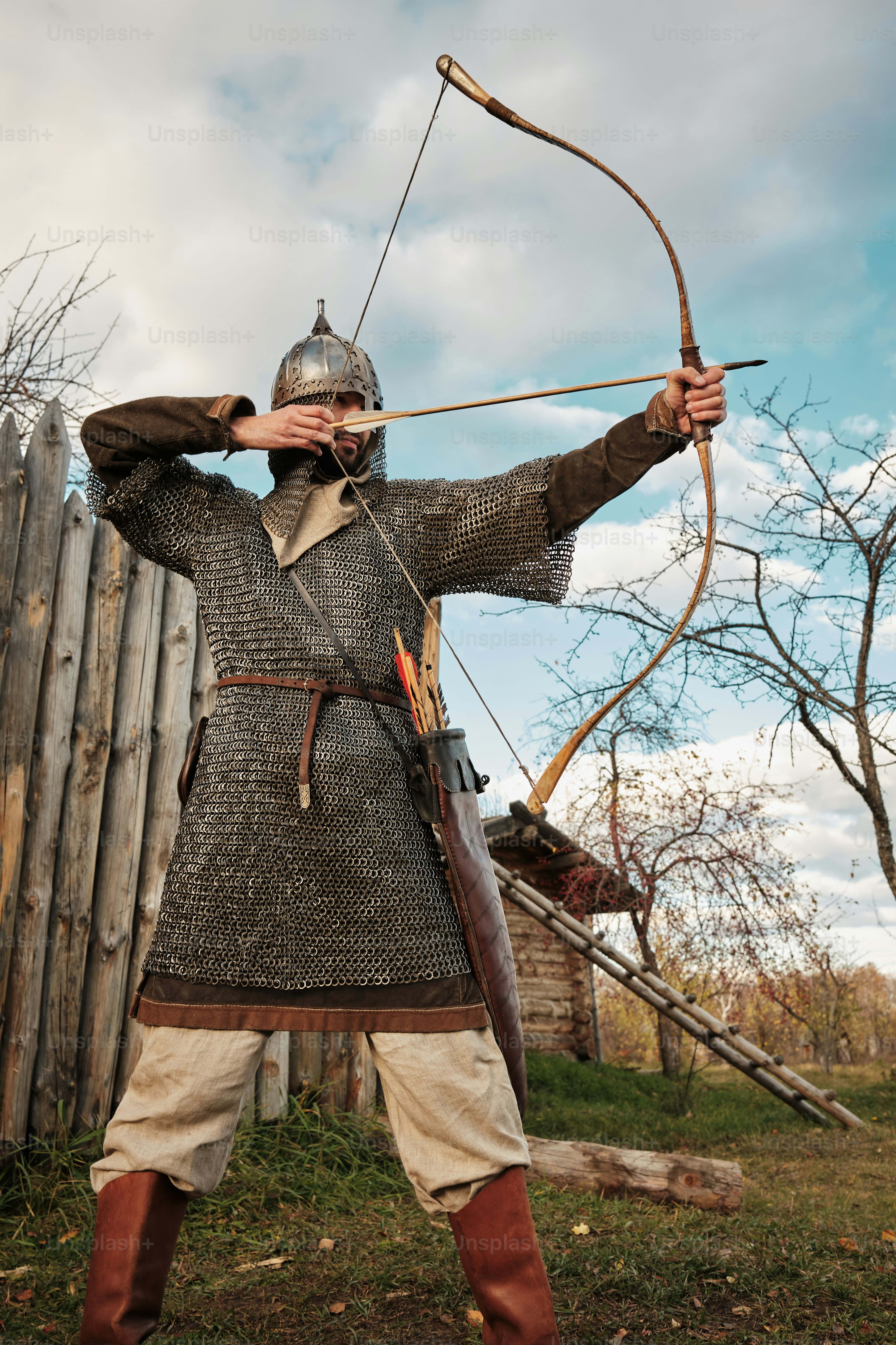 medieval archer in chain mail at the wooden wall of the settlement