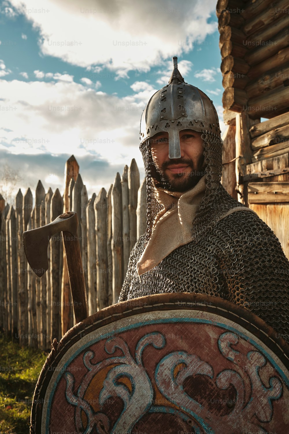a man dressed in armor standing next to a wooden fence
