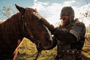 a man in armor is petting a horse