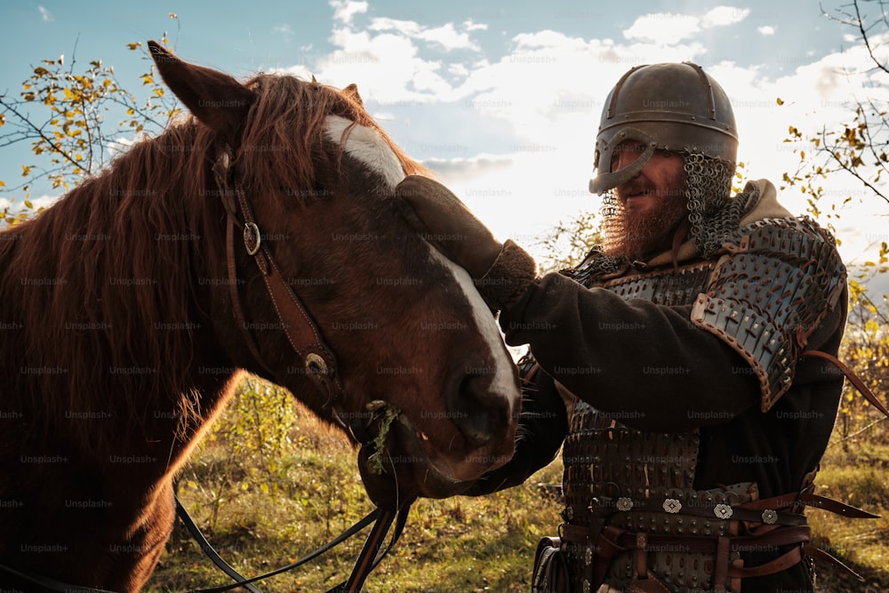 a man in armor is petting a horse