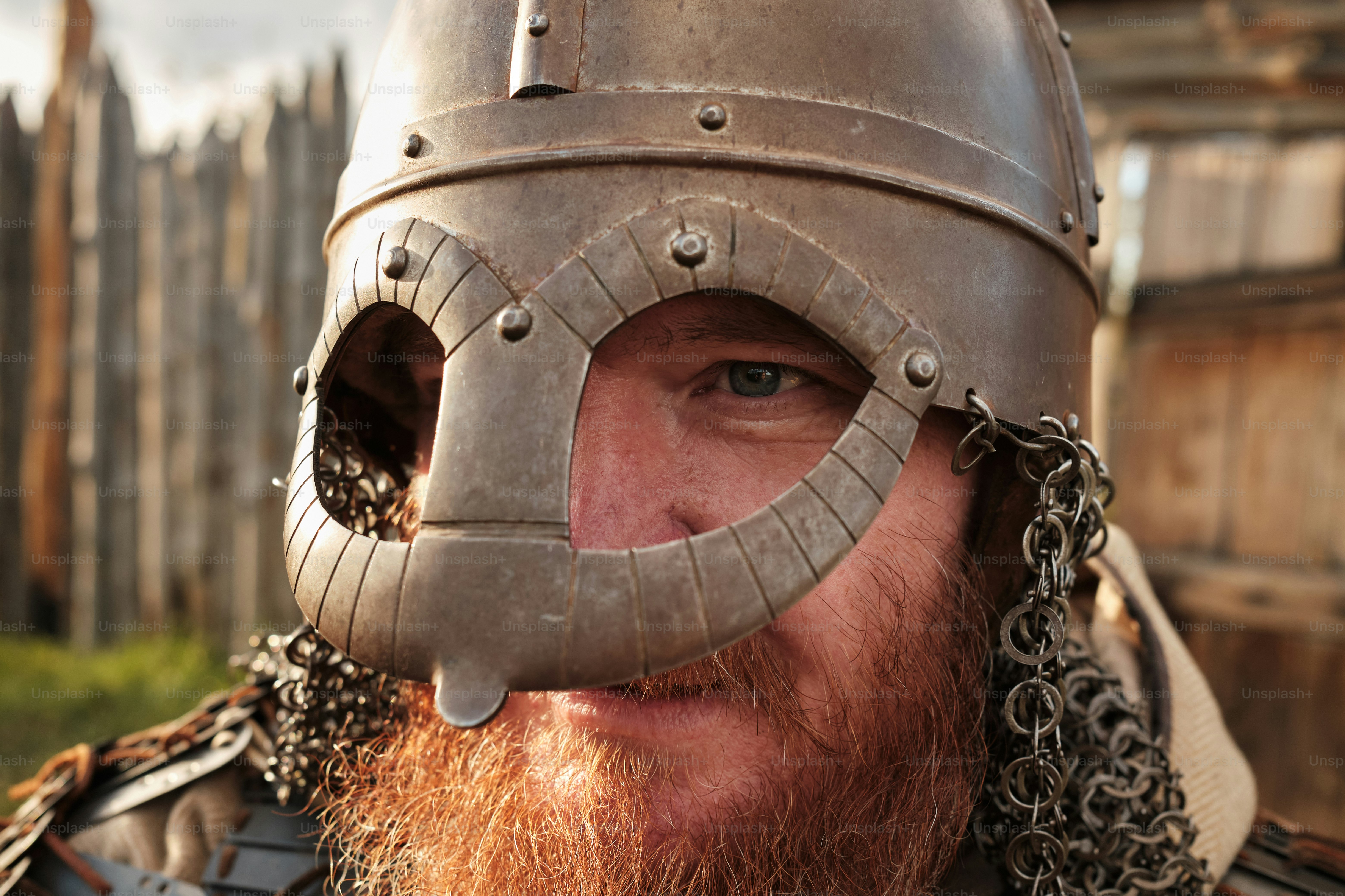Close up portrait of a medieval guard with a spear near a wooden gate of a medieval settlement