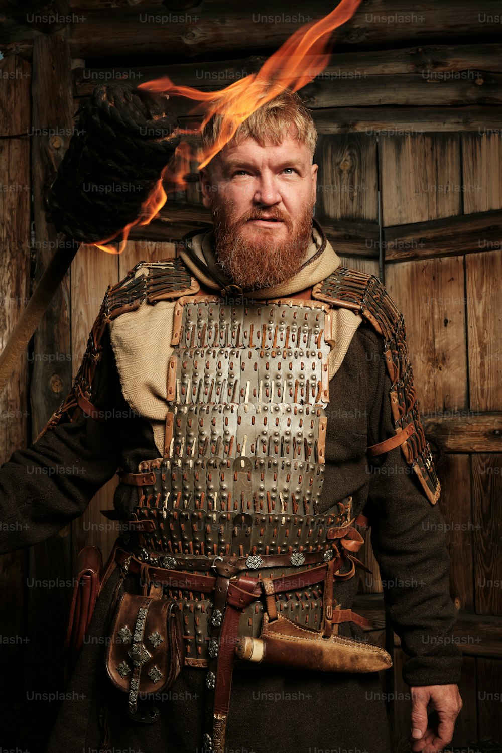Un hombre con un traje medieval con un fuego en la cabeza