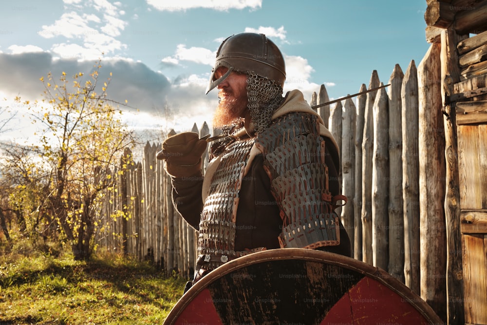 um homem vestido com armadura segurando uma espada e um escudo