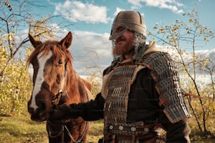 a man in armor standing next to a horse