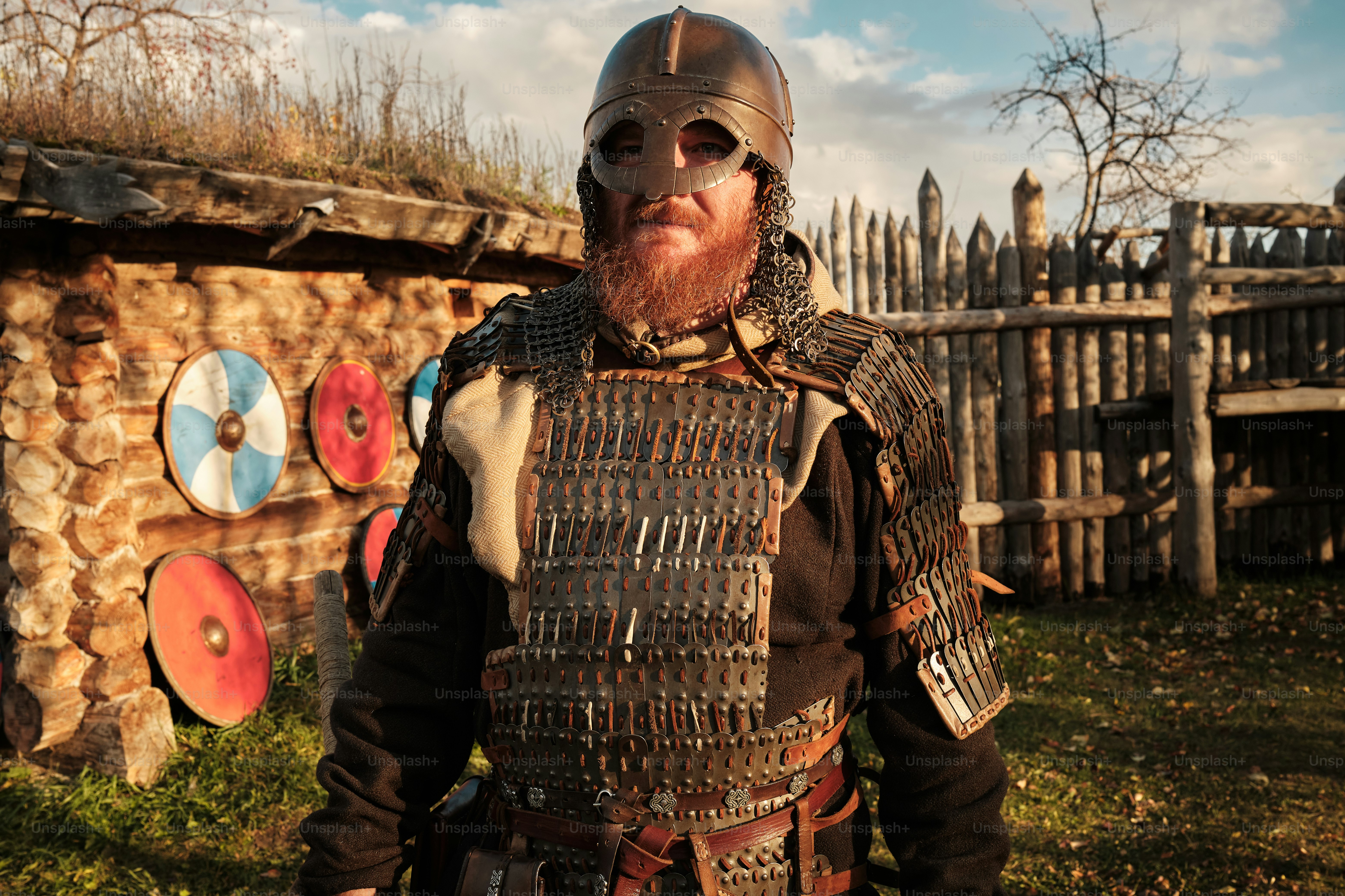 a man with a beard and a helmet standing in front of a fence