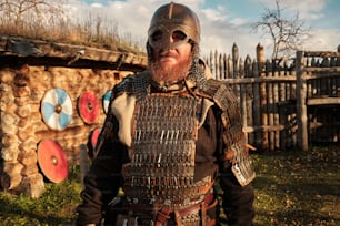 a man with a beard and a helmet standing in front of a fence