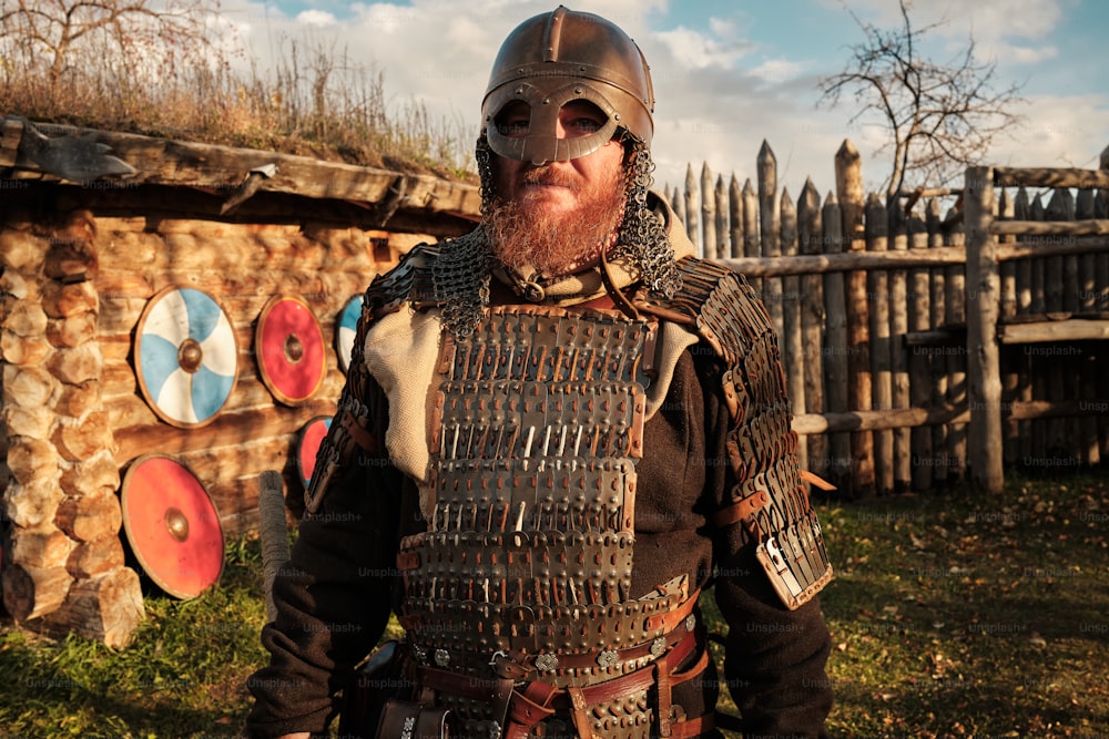 a man with a beard and a helmet standing in front of a fence