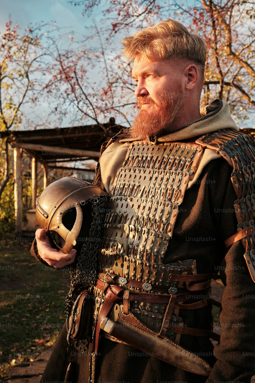 a man in a medieval costume holding a helmet