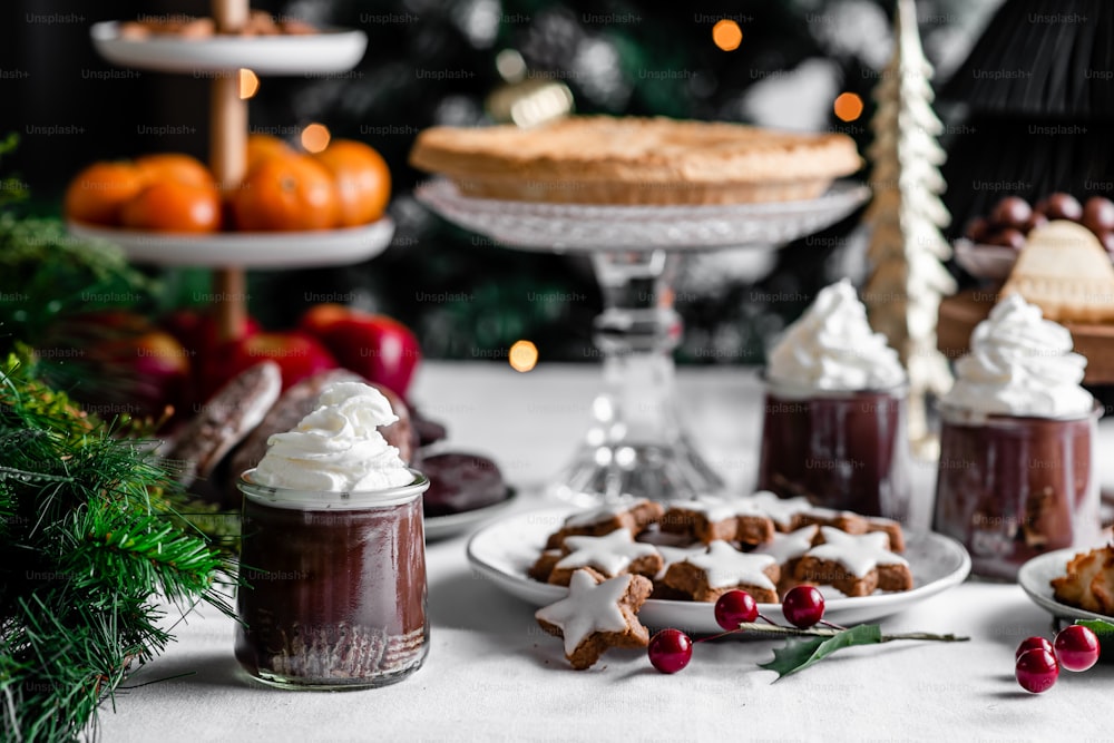 a table topped with cakes and desserts next to a christmas tree
