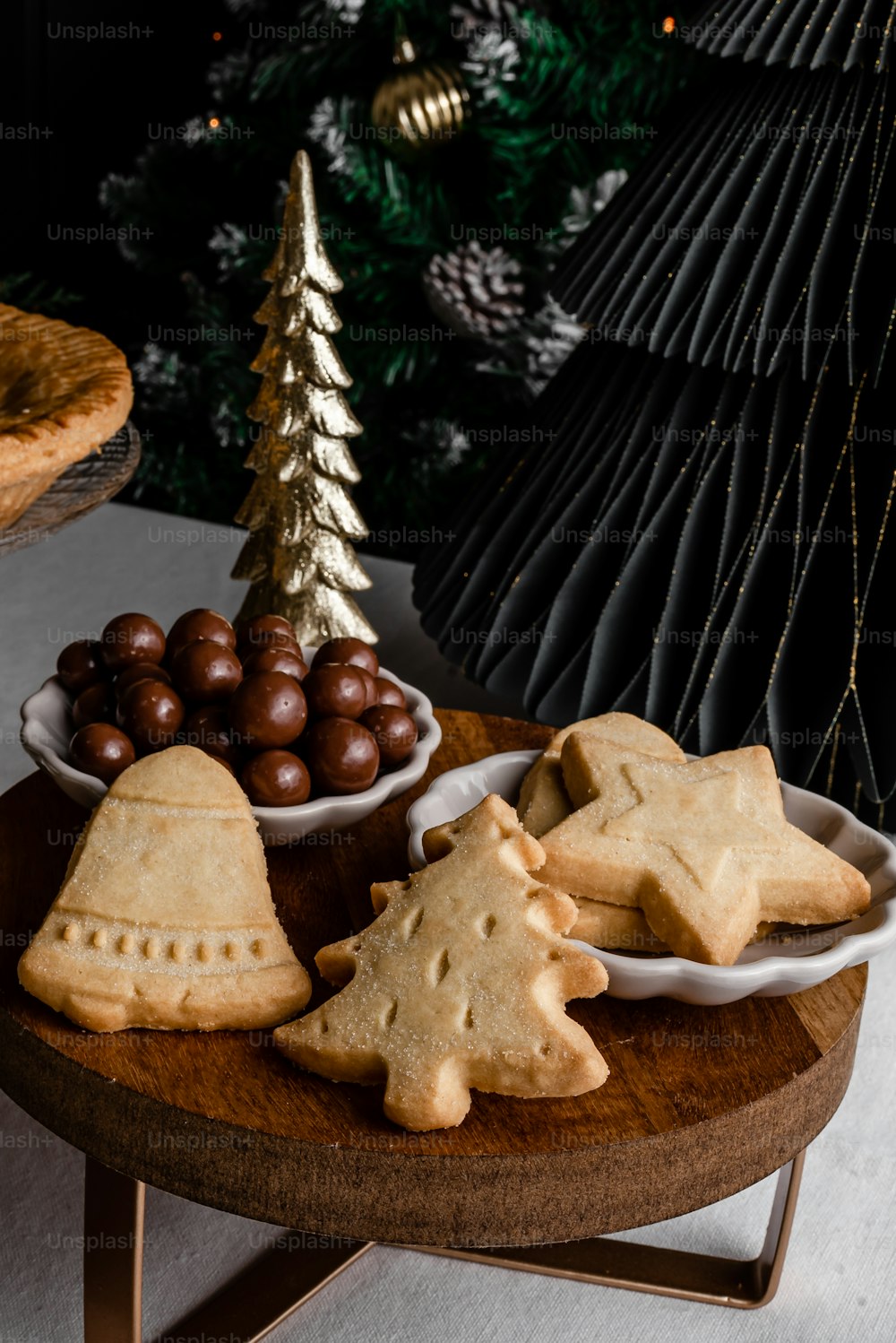 a wooden plate topped with cookies next to a christmas tree