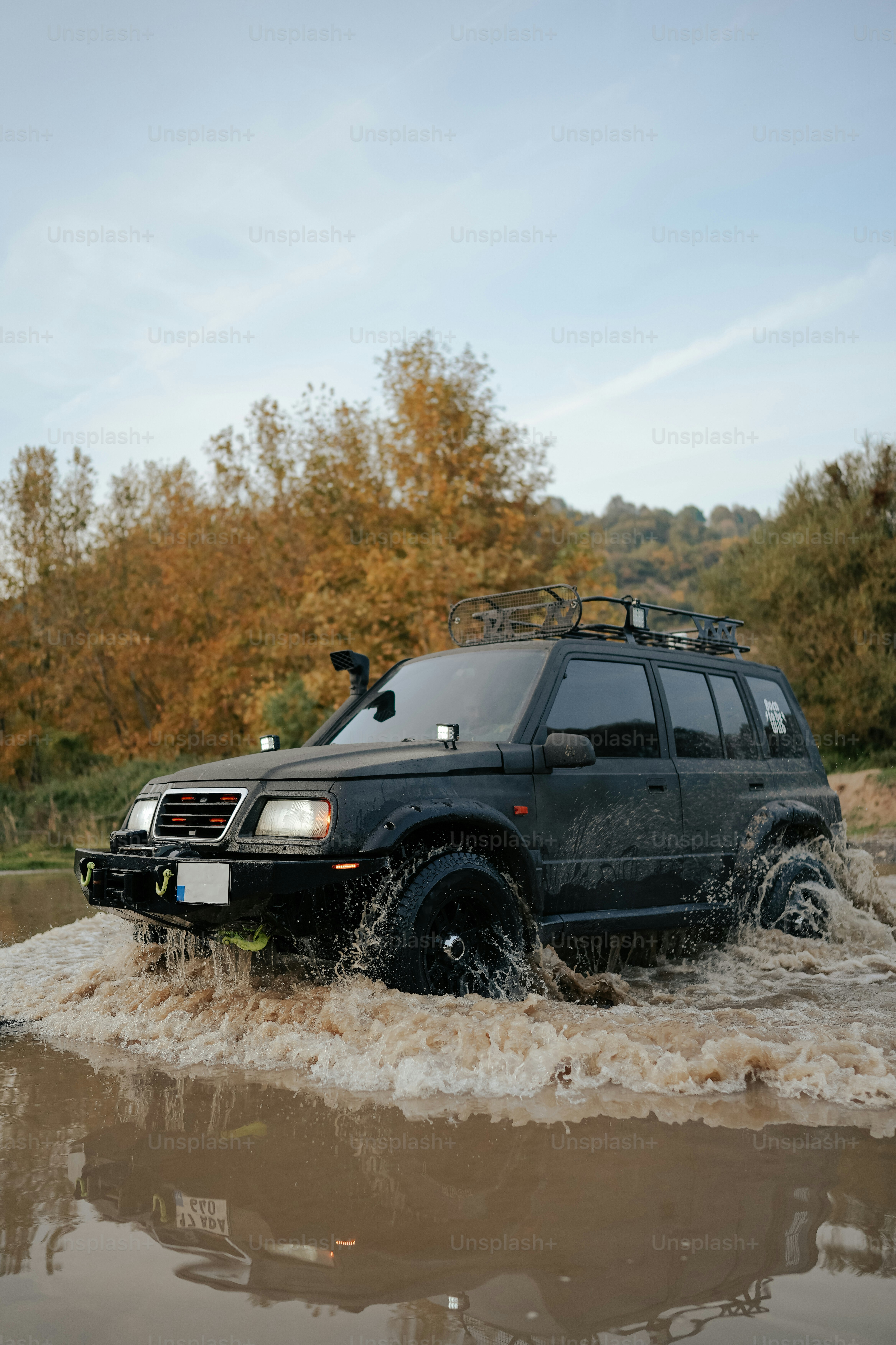 Un SUV noir circule dans une rivière boueuse