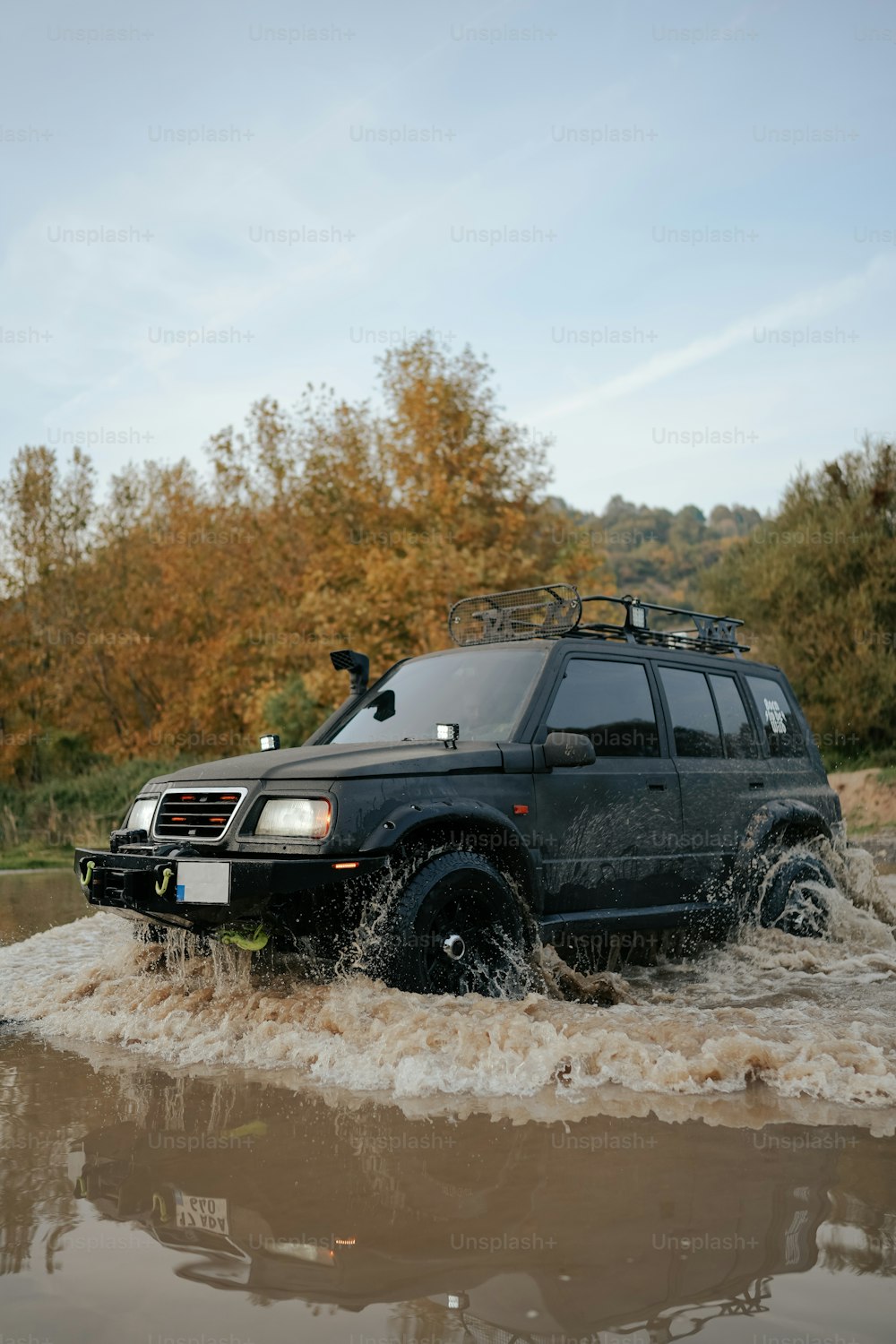 Un SUV negro conduciendo a través de un río fangoso
