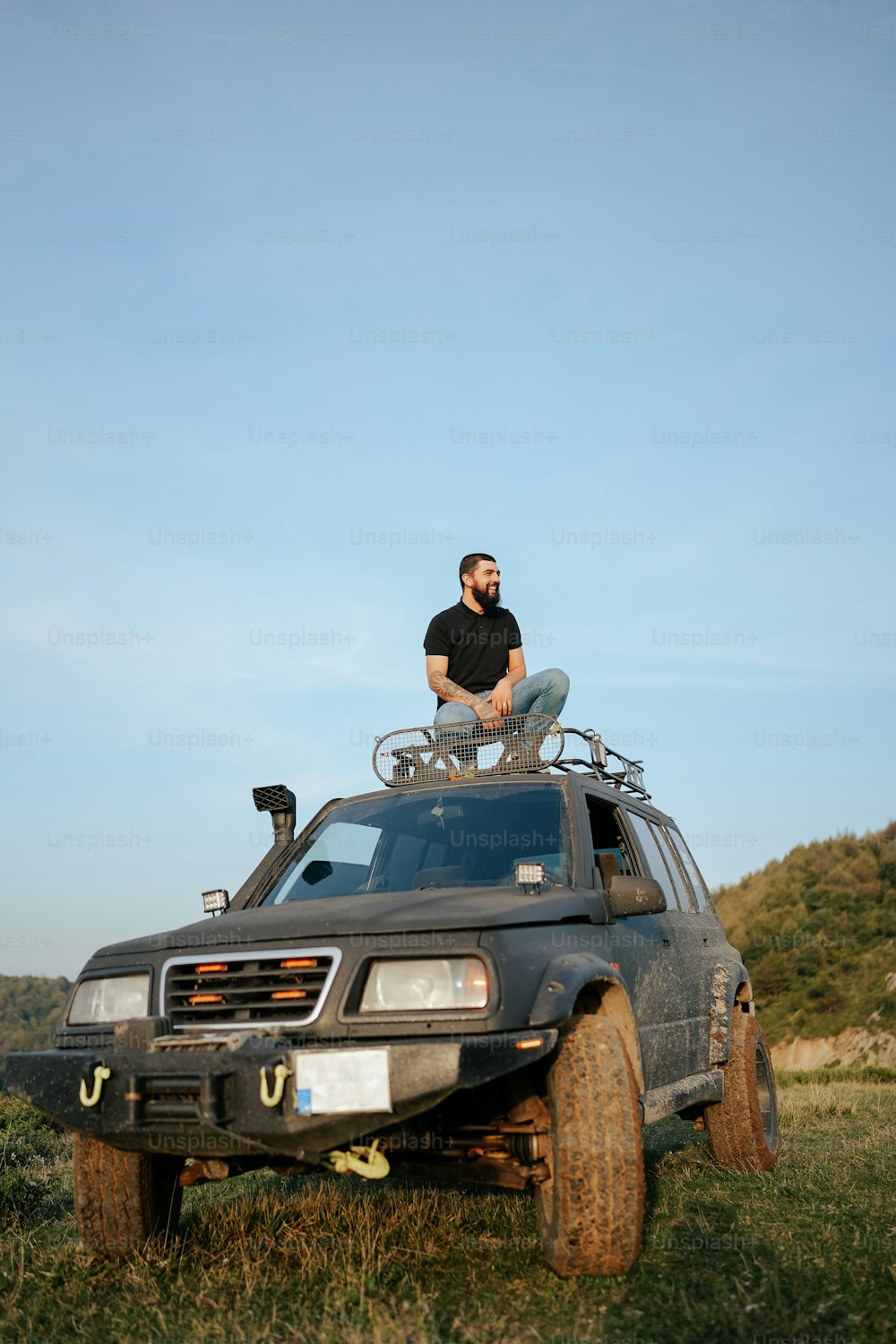 un uomo seduto sul tetto di un veicolo in un campo