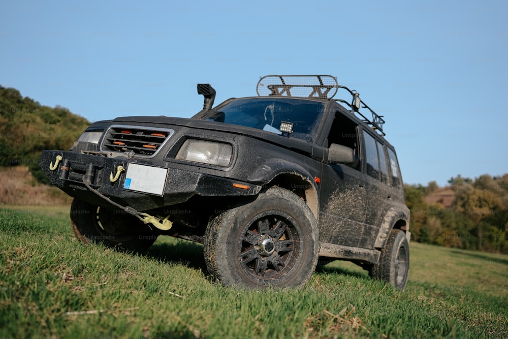 Un vehículo negro estacionado en un campo cubierto de hierba