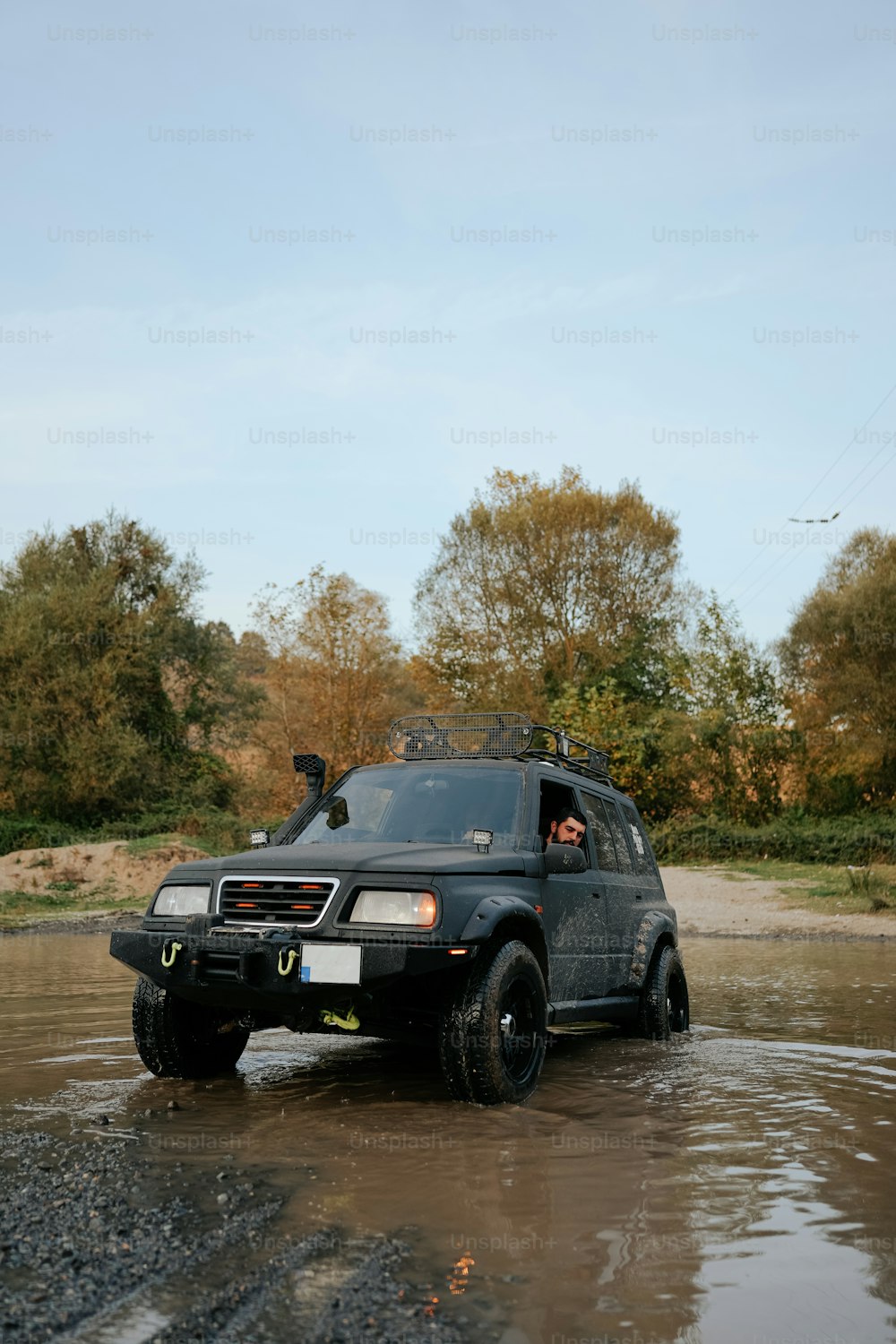 a black suv driving through a muddy road