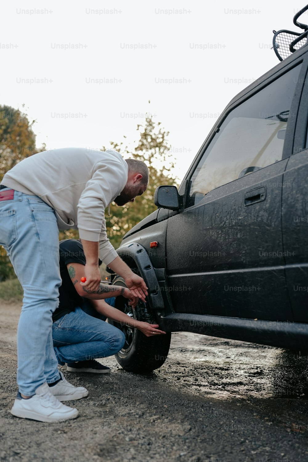 um homem consertando um pneu em um caminhão preto
