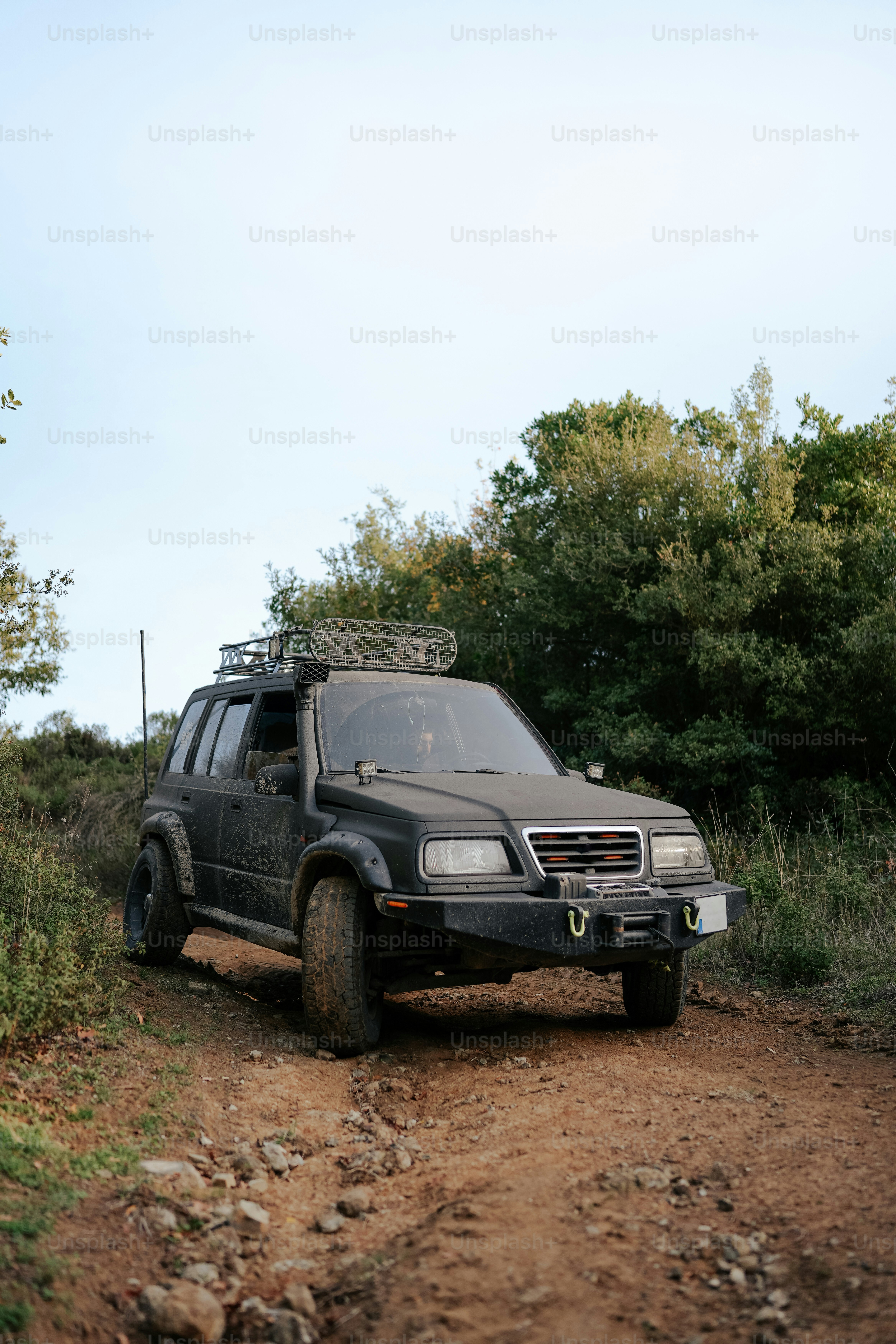 a black suv driving down a dirt road