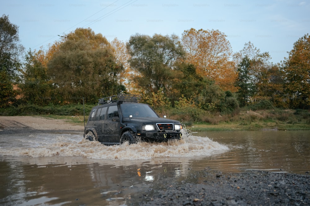 Un SUV negro conduciendo por una calle inundada