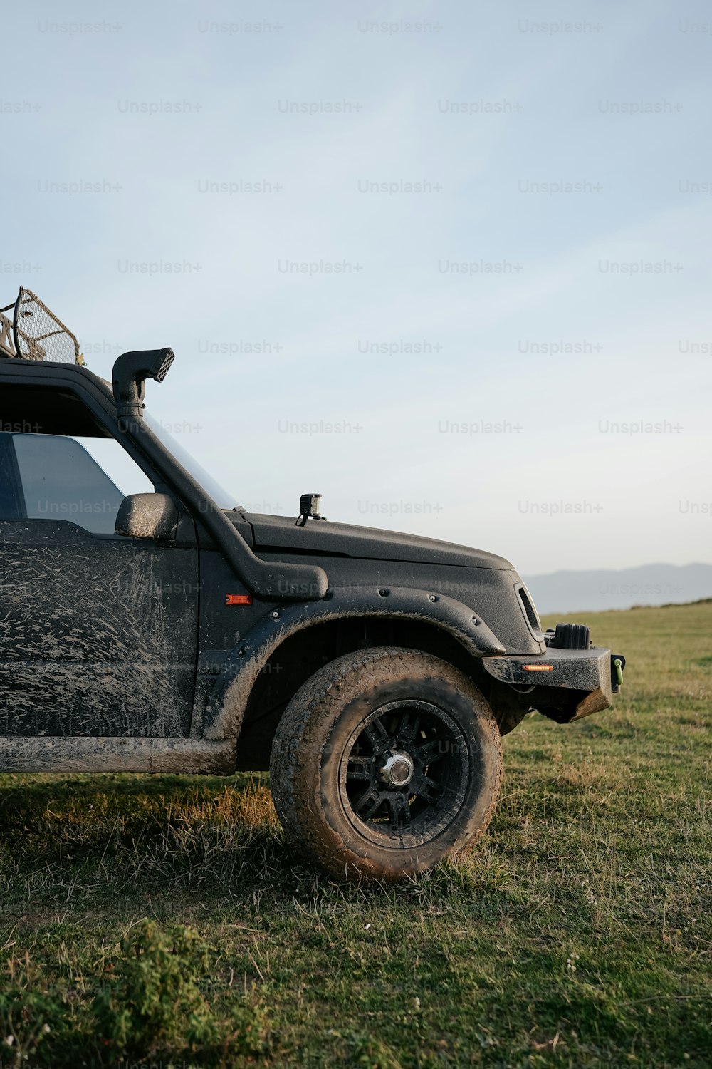 a black jeep parked on top of a lush green field