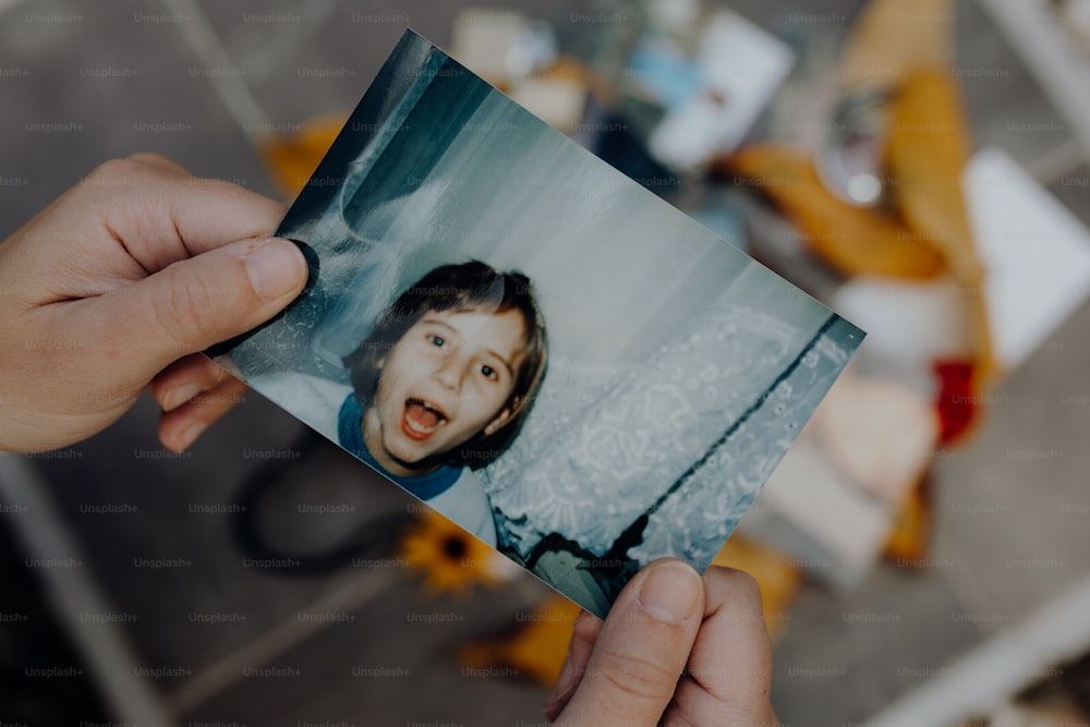 a person holding up a polaroid picture of a child