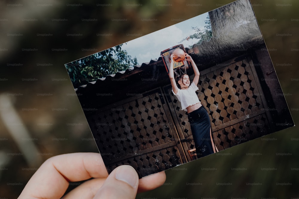 a person holding up a polaroid photo of a woman