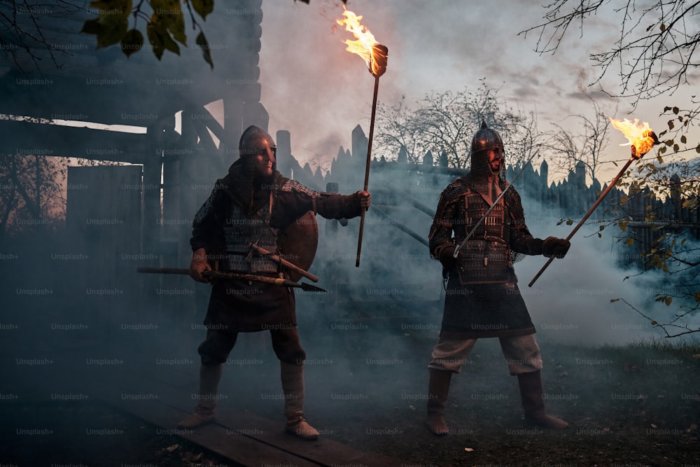 two men dressed in medieval costumes holding torches