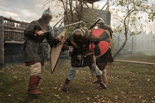 two men dressed in medieval armor fighting in a park