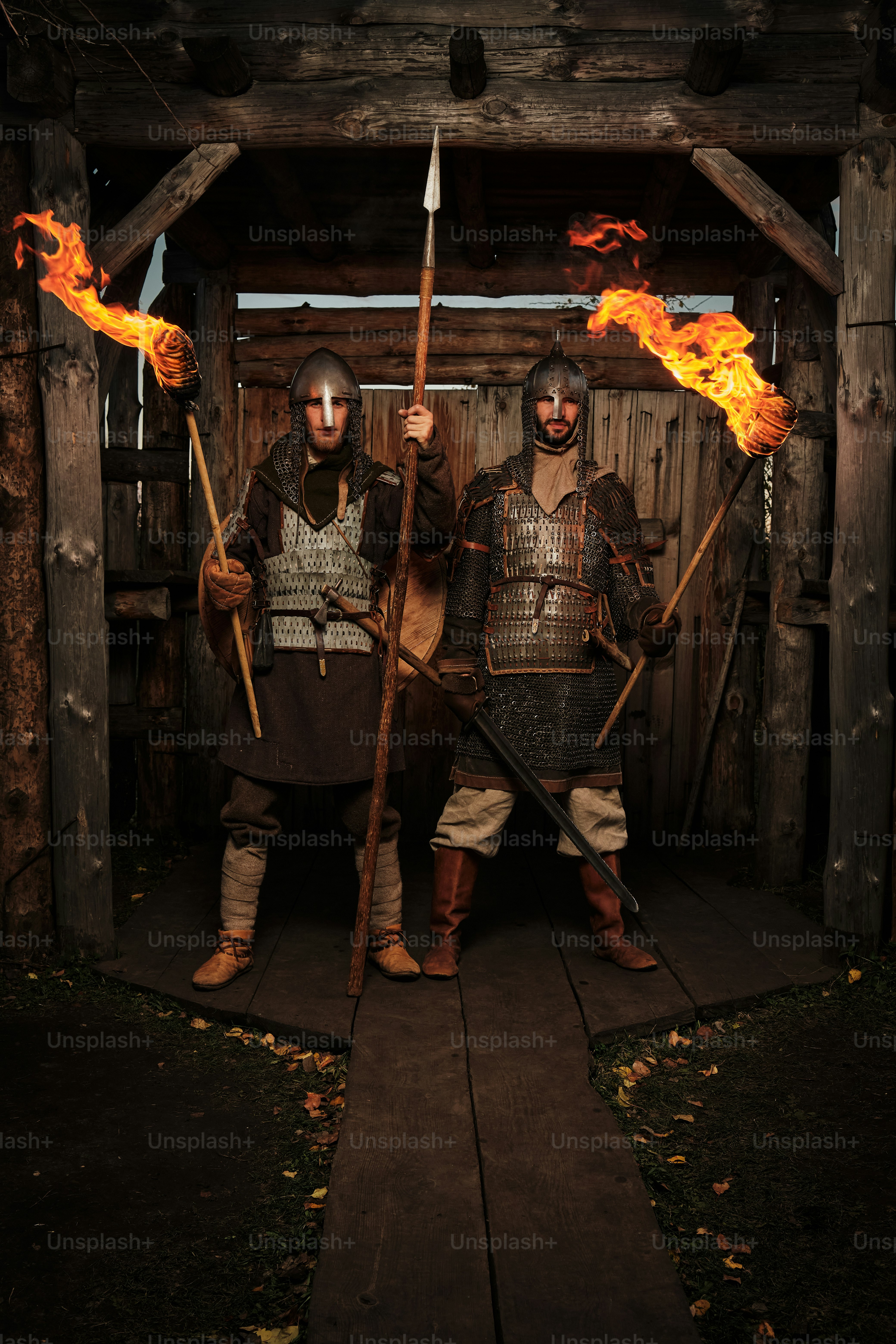 Due uomini vestiti con un'armatura medievale che reggono torce