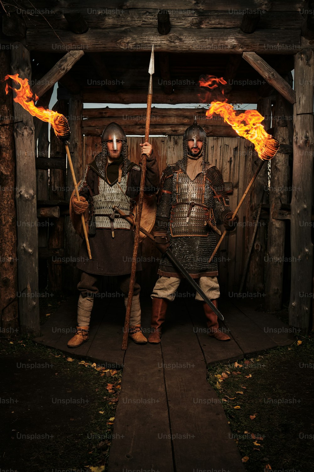 two men dressed in medieval armor holding torches