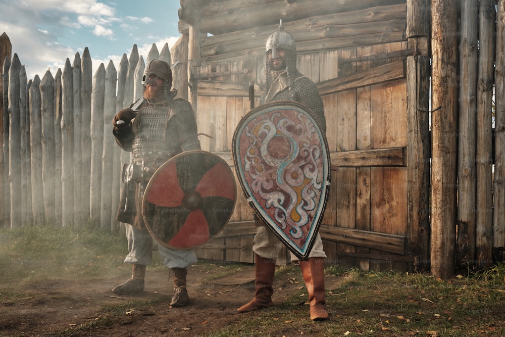 Un par de hombres parados uno al lado del otro sosteniendo escudos