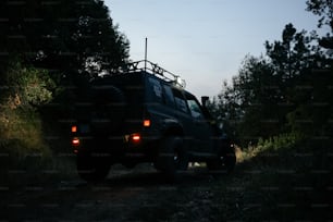 une jeep roulant sur un chemin de terre à côté d’une forêt