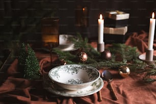 a table topped with plates and candles next to a christmas tree