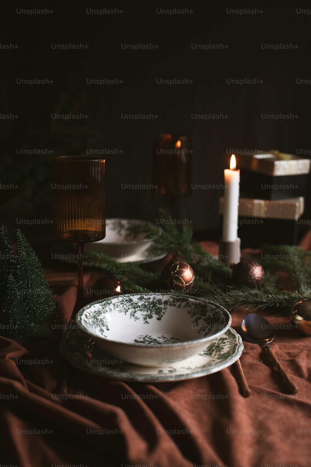 a table topped with plates and candles next to a christmas tree