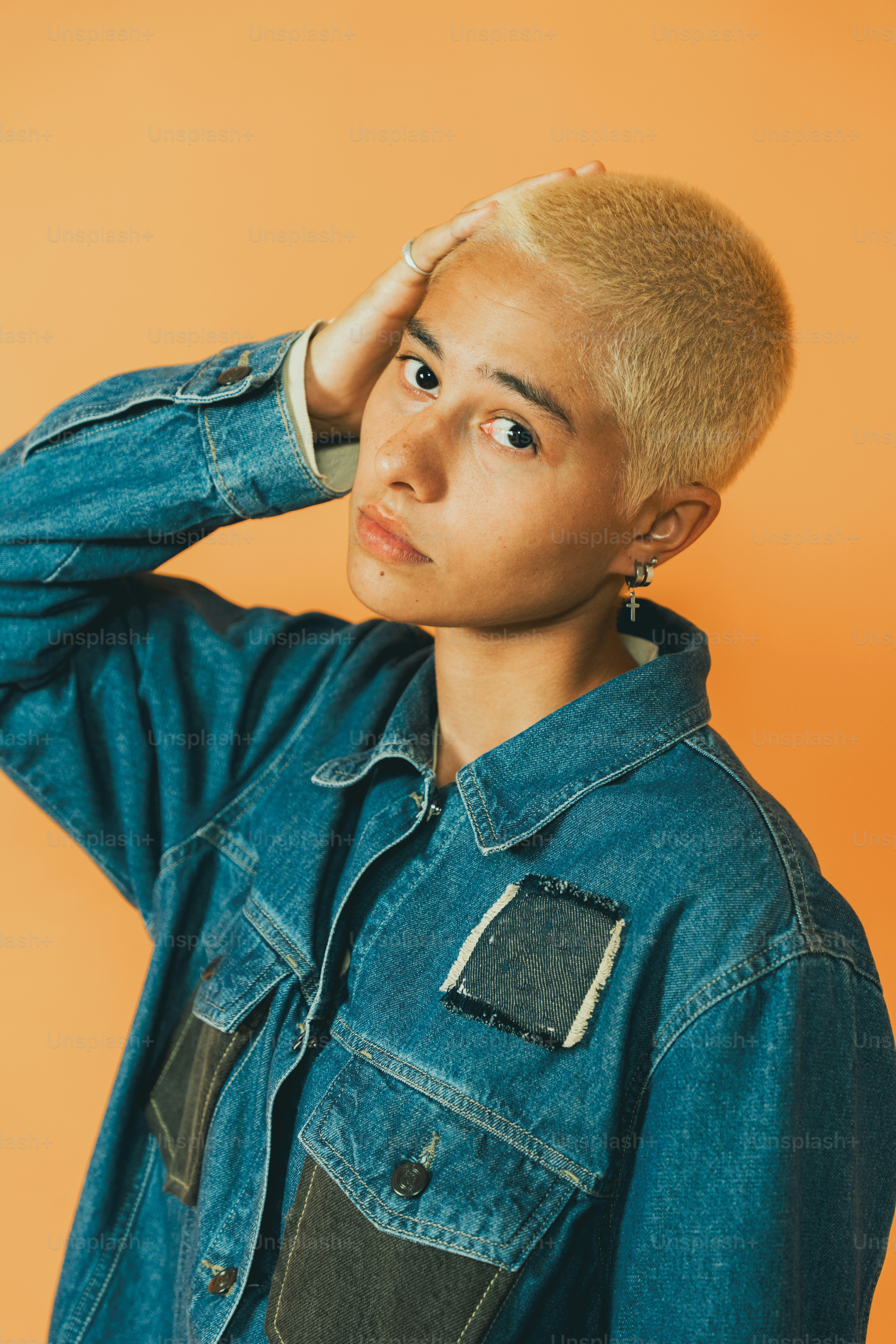 a young man with a shaved head wearing a denim jacket