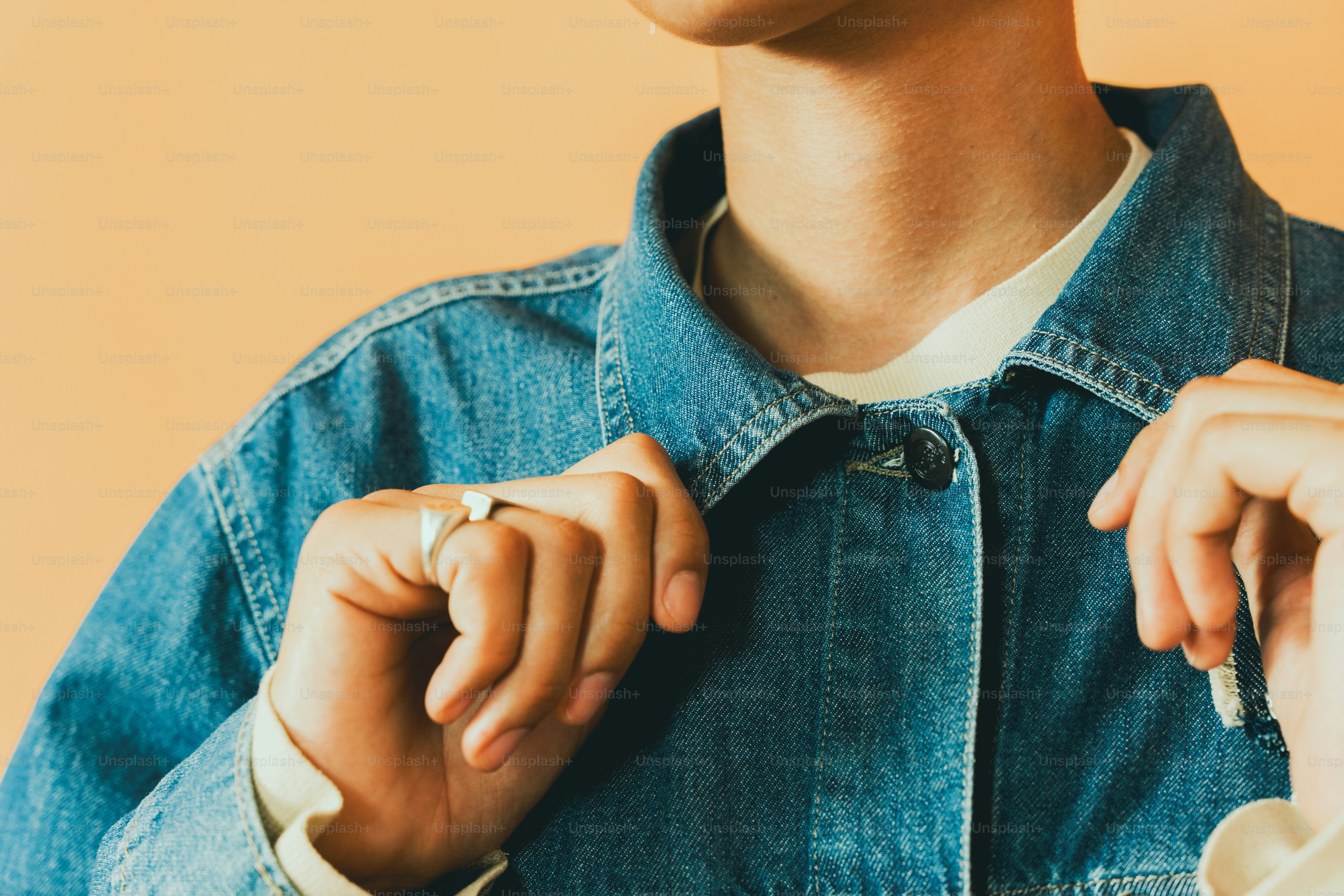 a person wearing a denim jacket and a ring