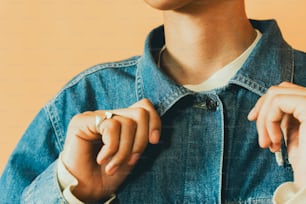 a person wearing a denim jacket and a ring