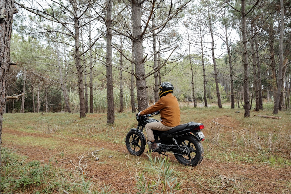 un homme conduisant une moto à travers une forêt