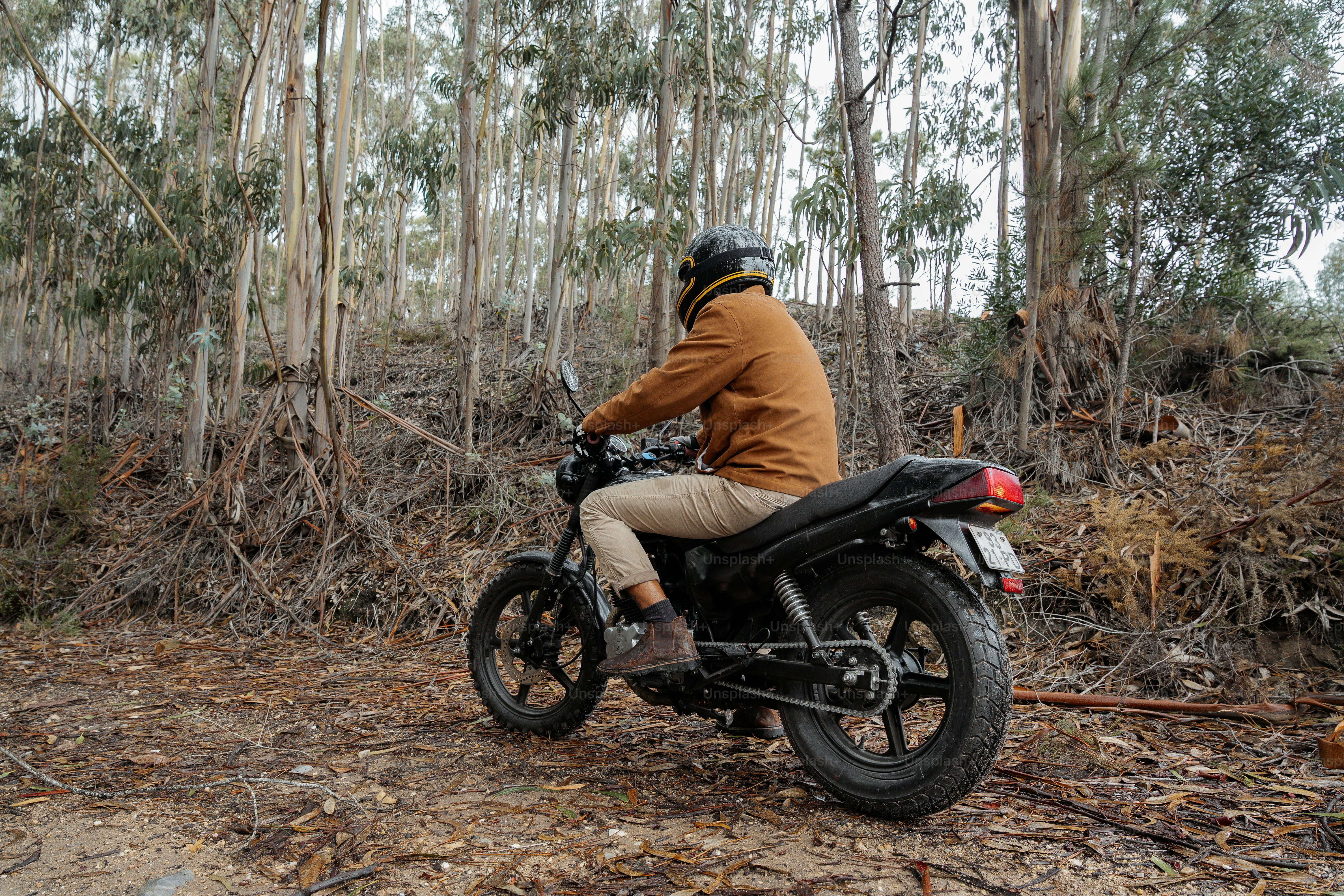 a man riding a motorcycle through a forest