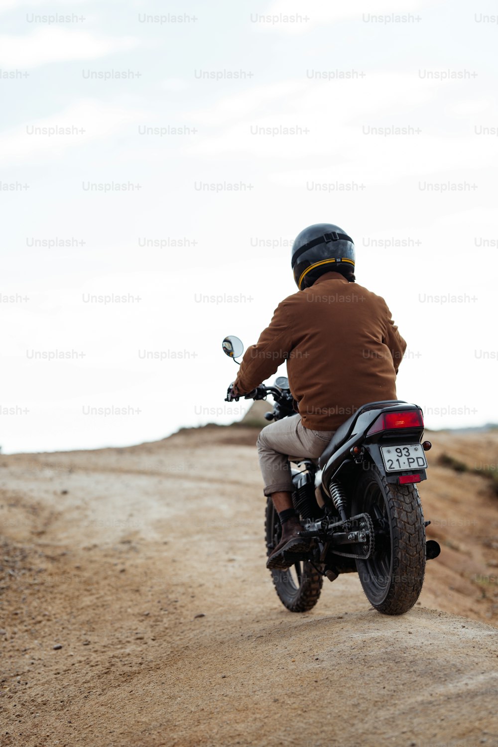 ein Mann, der mit einem Motorrad eine unbefestigte Straße hinunterfährt