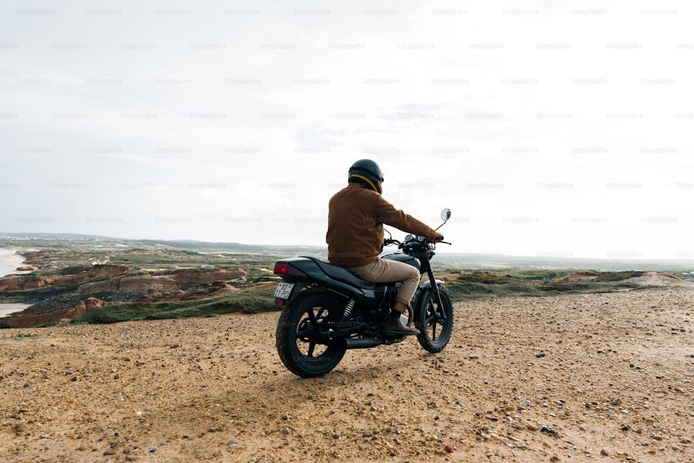 Un hombre montando una motocicleta en la parte superior de una playa de arena