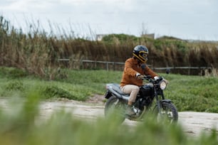 um homem pilotando uma motocicleta por uma estrada de terra