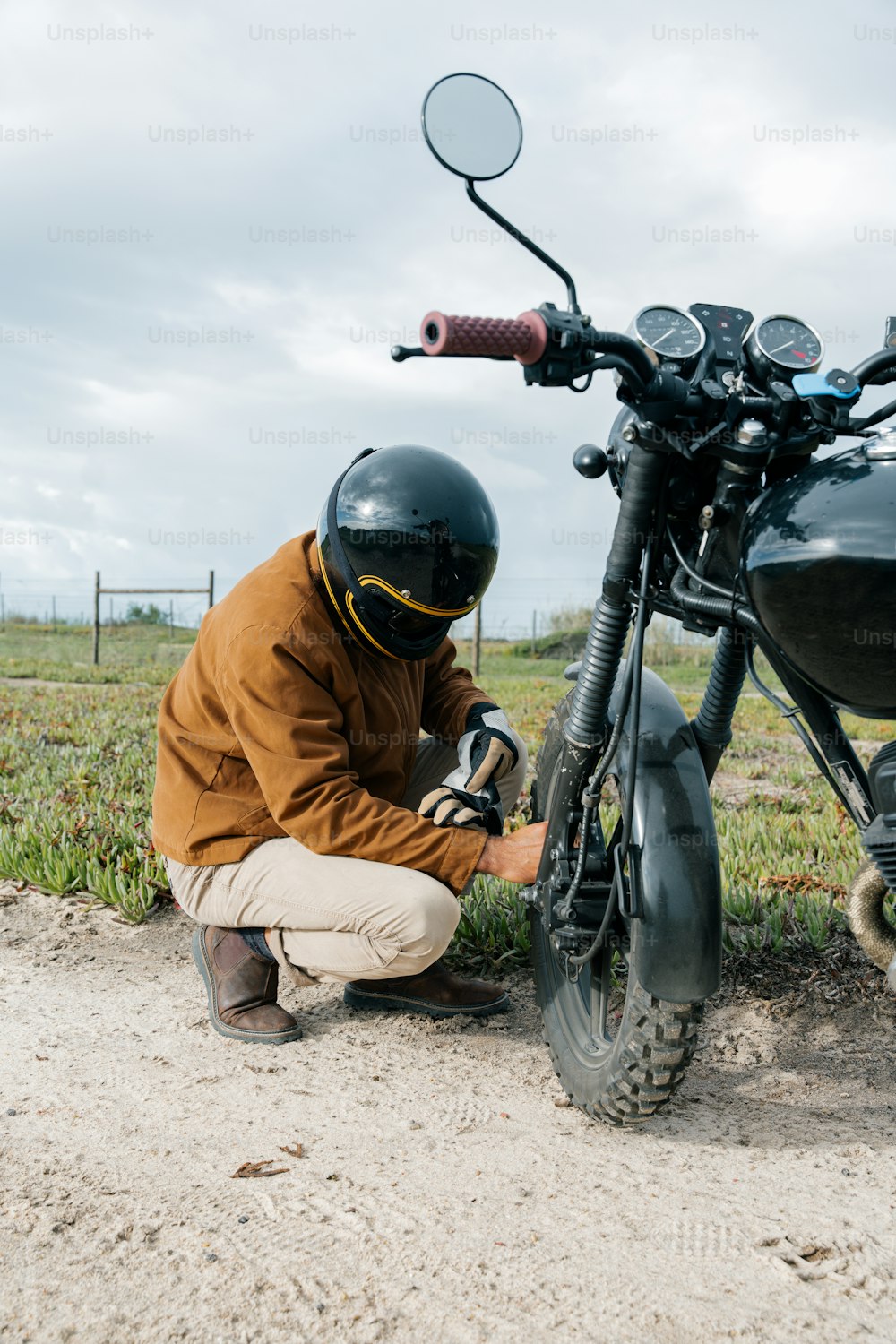 Un hombre arrodillado junto a una motocicleta