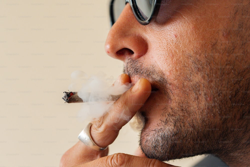 un homme à lunettes fumant une cigarette