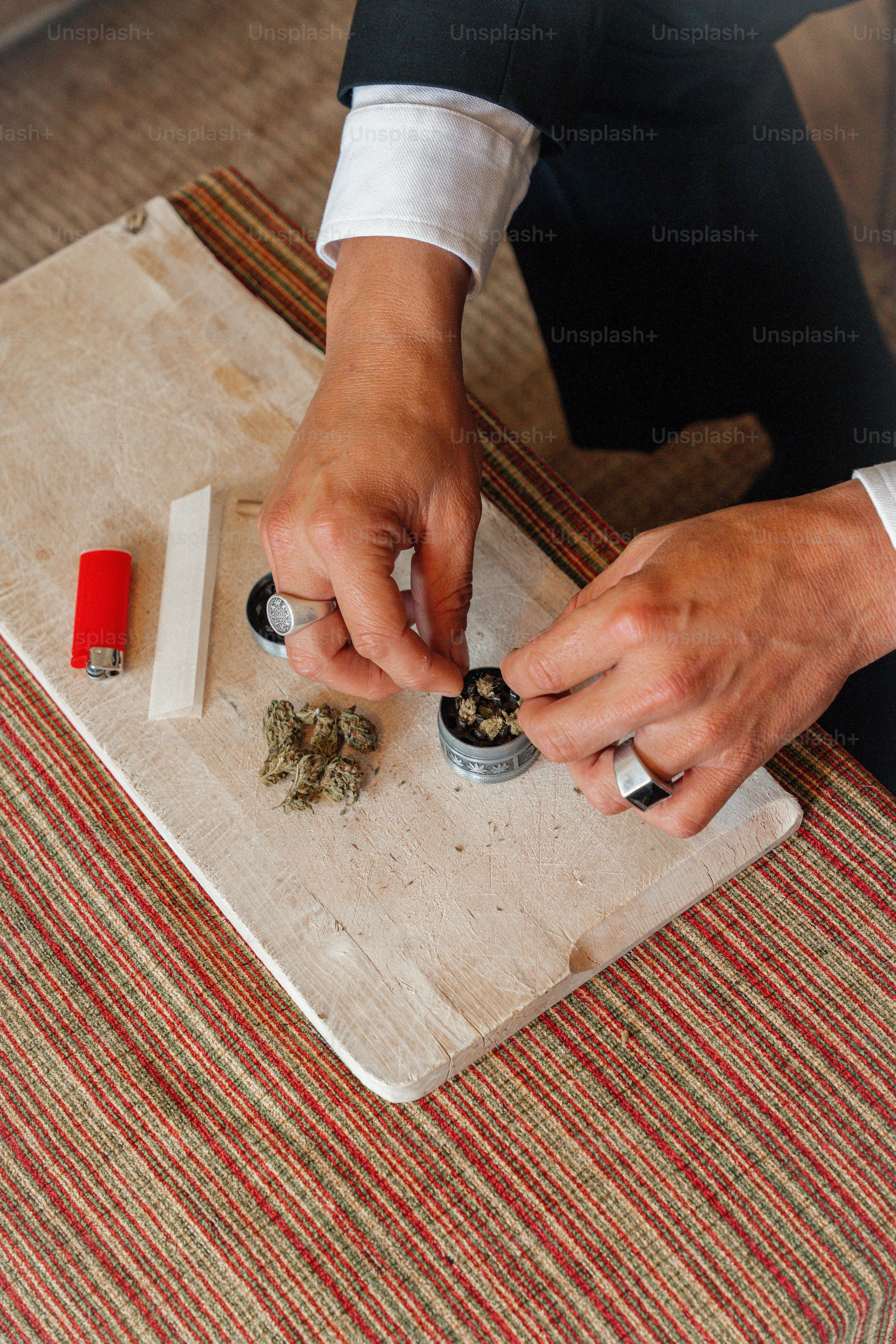 a man in a tuxedo sitting at a table with a tray of marijuana