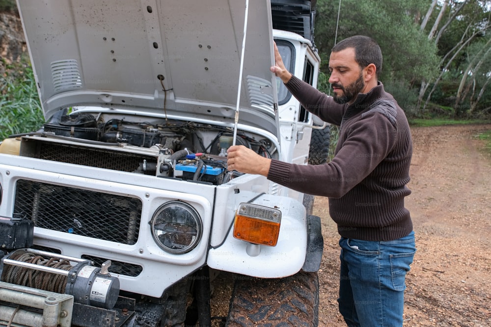 a man standing next to a white truck with its hood open